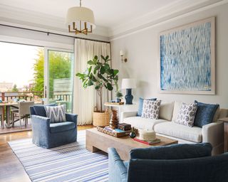 Light, bright blue and cream living room, sofa, seating, window leading to terrace, artwork on wall