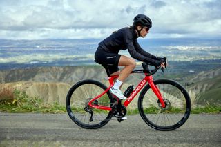 A female cyclist rides a red Pinarello X in the mountains