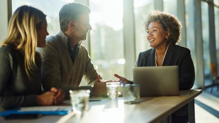 Cheerful financial adviser communicating with a couple during a meeting in an office.