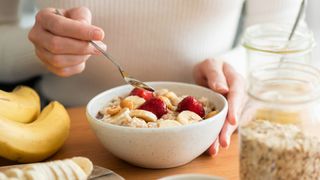 woman eating a healthy breakfast of oatmeal and fruit