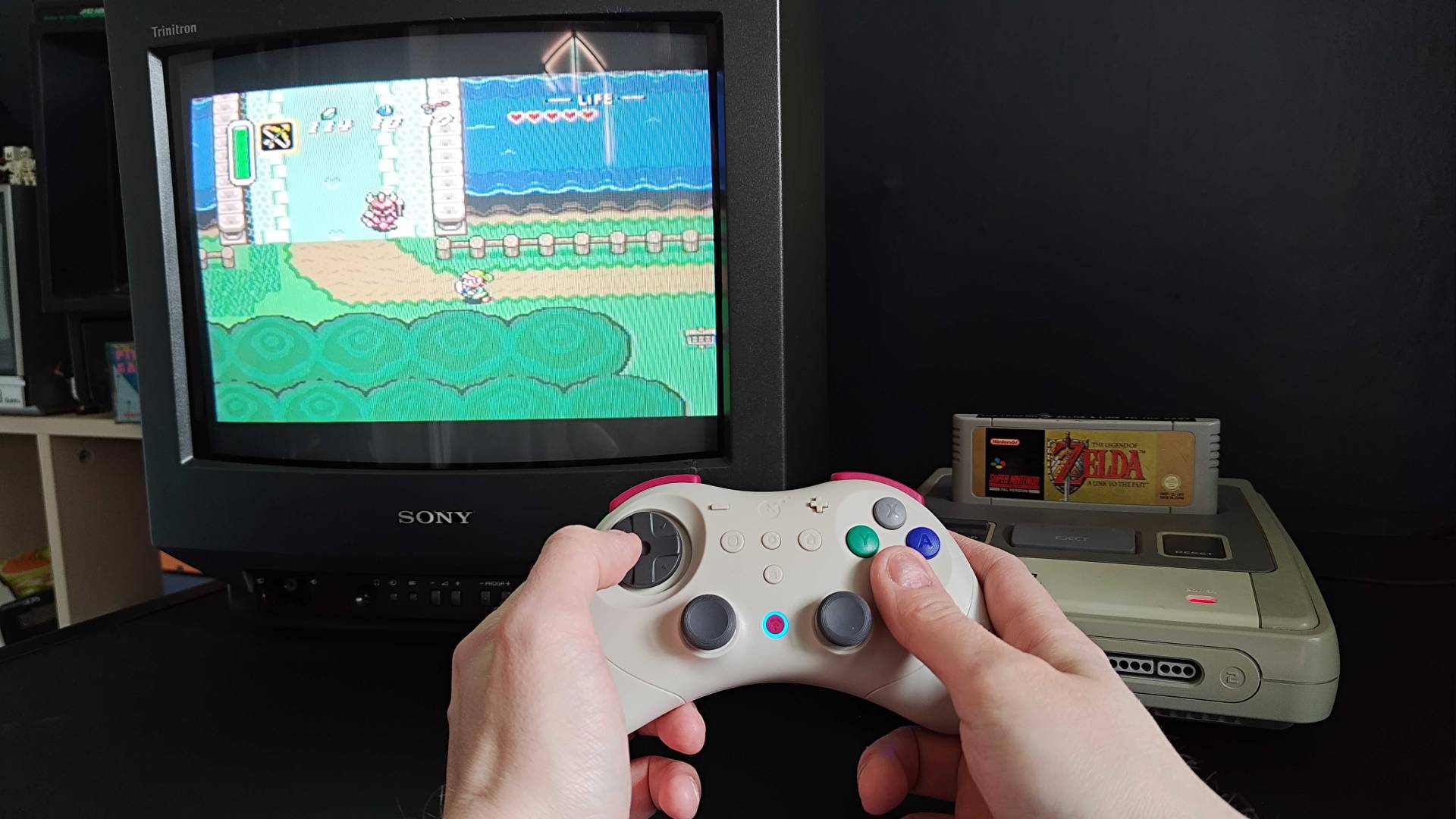 Hands using Gulikit Elves 2 Pro to play The Legend of Zelda: A Link to the Past on a SNES connected to a Sony Trinitron CRT TV.