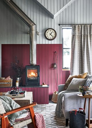 Cosy living room with claret red painted wooden slat walls with a cosy log burner