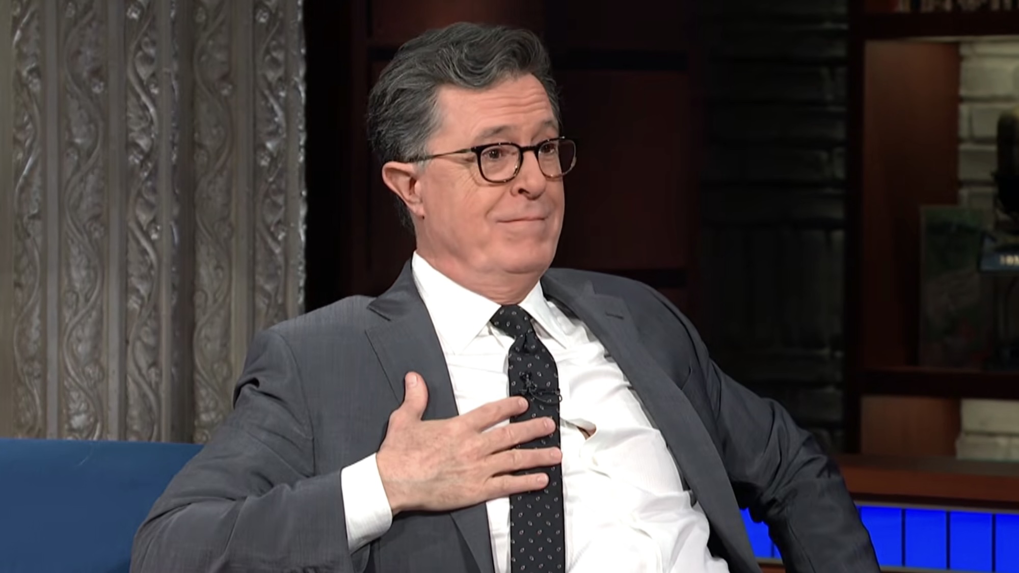 Stephen Colbert holding hand to chest while talking to Jon Baptiste on The Late Show