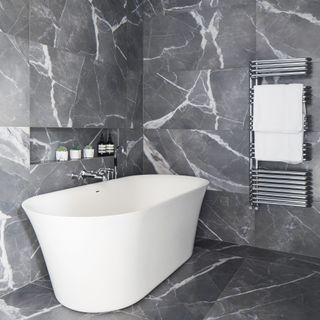 Bathroom with oversized grey and white marble tiles and white bath tub