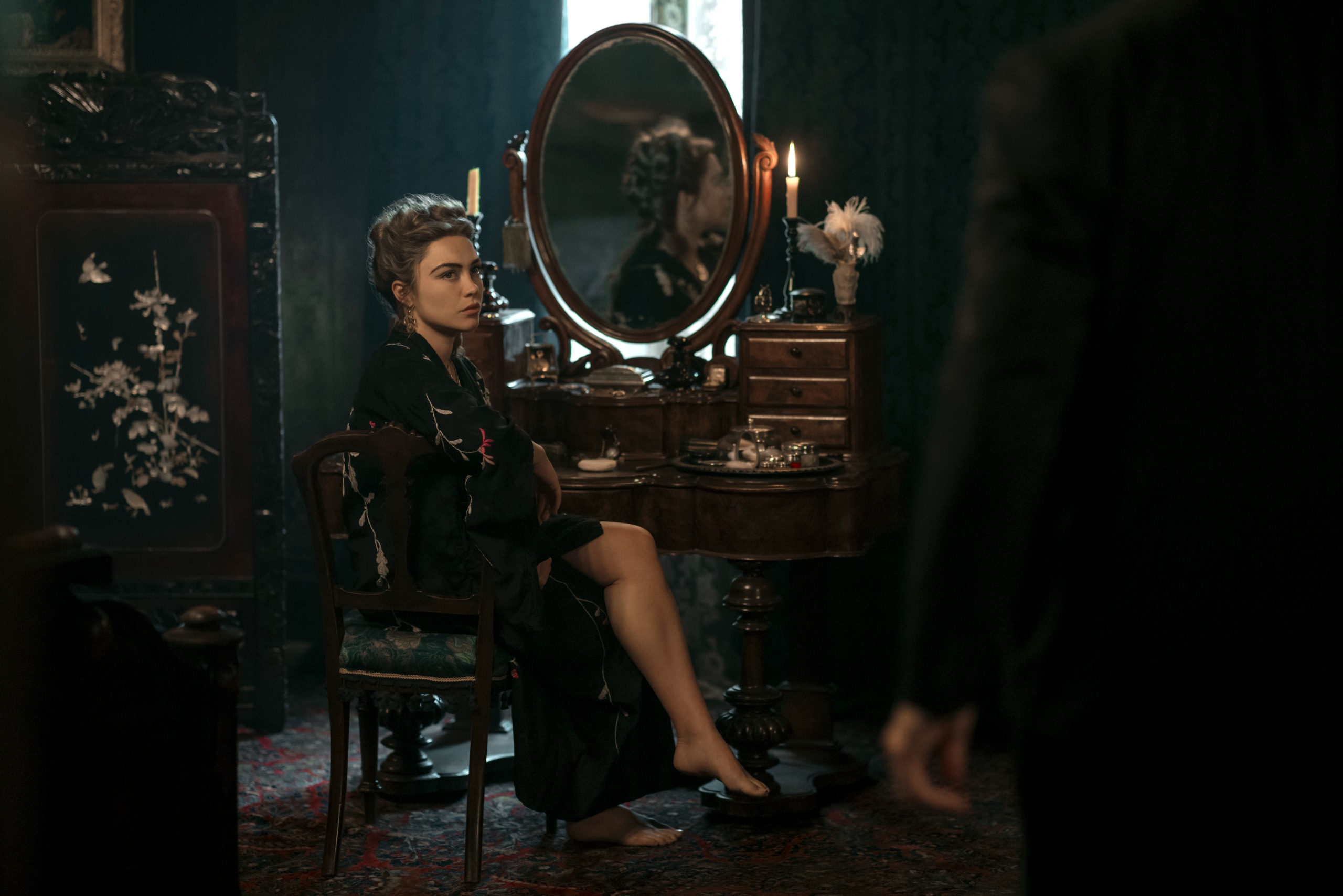florence pugh as cathy ames wearing a black robe sitting at a vanity looking over her shoulder in east of eden