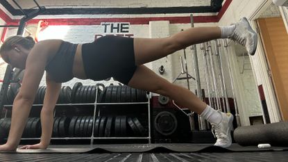 Woman doing plank leg raises in a gym