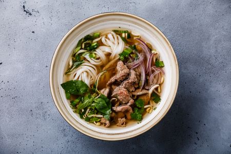 Bowl of noodle soup on concrete background