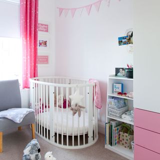 White nursery with scandi style white cot and pink accents on curtains and furniture