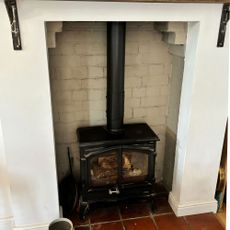 cast iron log burner in small inglenook fireplace on quarry tile hearth