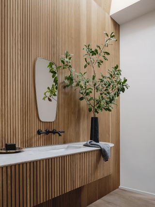 bathroom with pale natural wood panelling and white walls