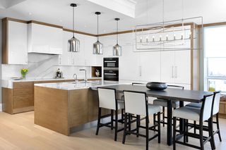 A kitchen with a white countertop and a long dining with chairs
