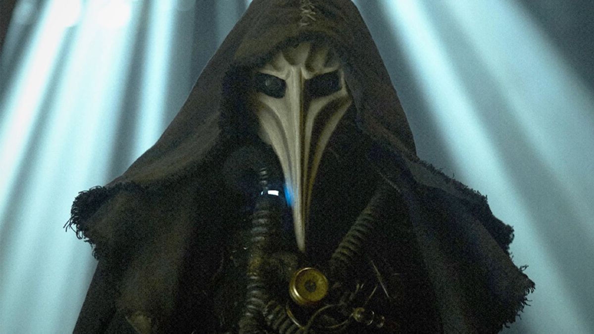 A person wears a plague doctor skull mask with a dark cloak and dramatic spotlight lighting behind them 