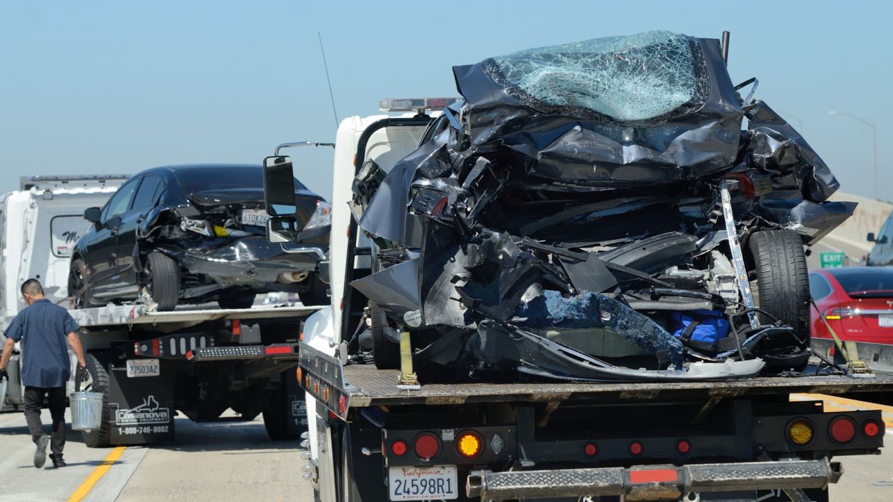 A Tesla and a Honda Civic sit on tow trucks following an accident in Seal Beach, California.