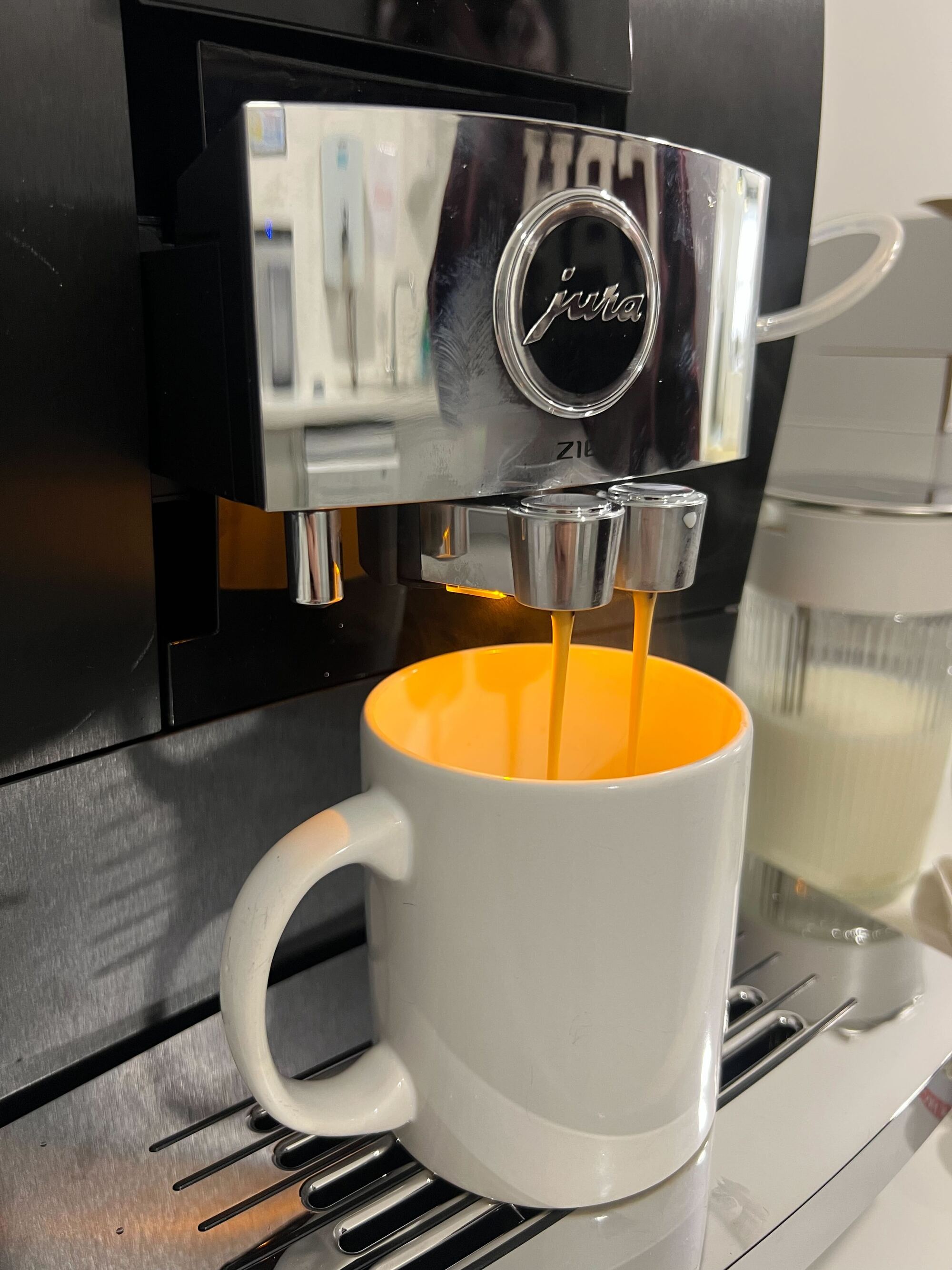 An espresso shot brewing from a black Jura Z10 coffee machine into a white mug