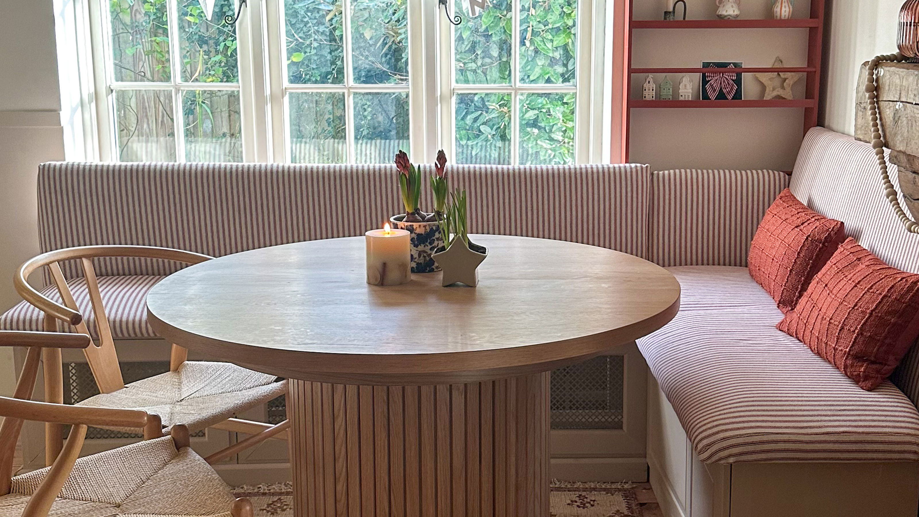 Striped kitchen banquette seating around round wooden table