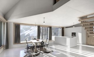 Interior view of Modern Chalet featuring white walls, large windows with grey curtains, a dining table and the kitchen area