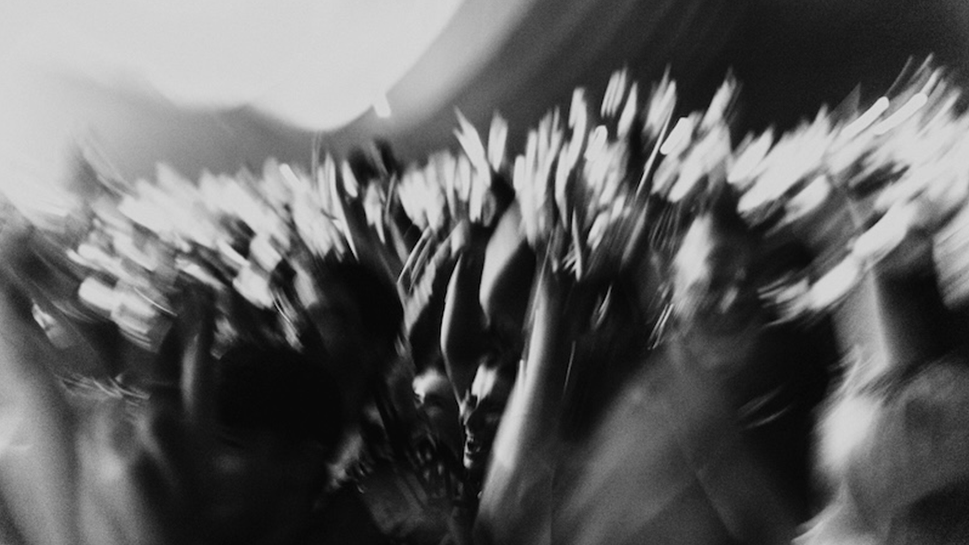 A group of people at Fred again..'s USB002 tour concert hold their phone-free hands in the air