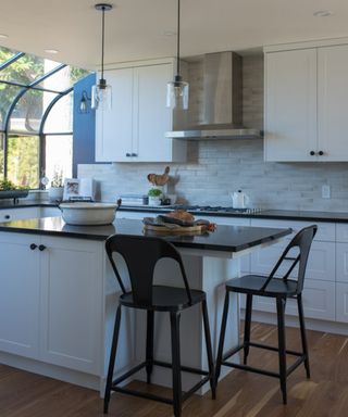 Neutral kitchen scheme with tonal subway tiles on wall, and warm wooden flooring, and white kitchen island.