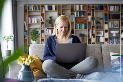 Woman at home sitting on sofa using laptop