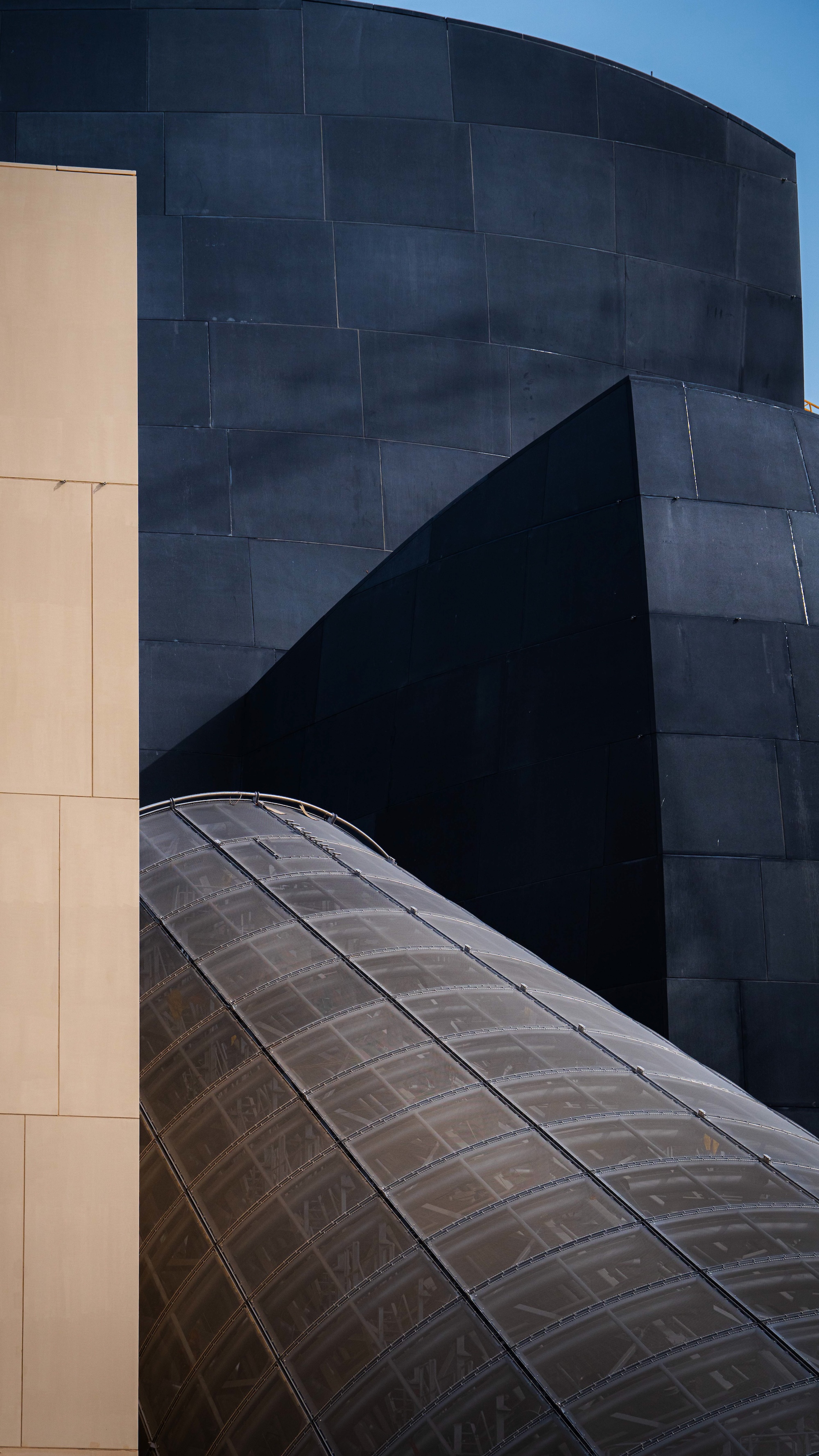 Guggenheim Abu Dhabi exterior images featuring a geometric assemblage of volumes made from steel glass timber and stone