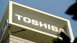 A zoomed in photo of a building bearing the Toshiba logo, shot from a low angle and partially obscured by out of focus leaves
