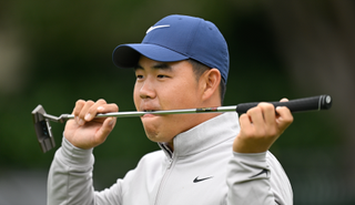 Tom Kim bites down on his putter