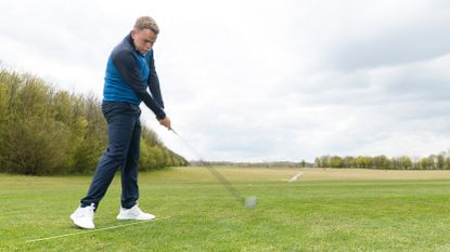 Tour coach Liam James hitting a fairway wood