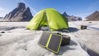 Solar panel charger with tent in background at remote campsite