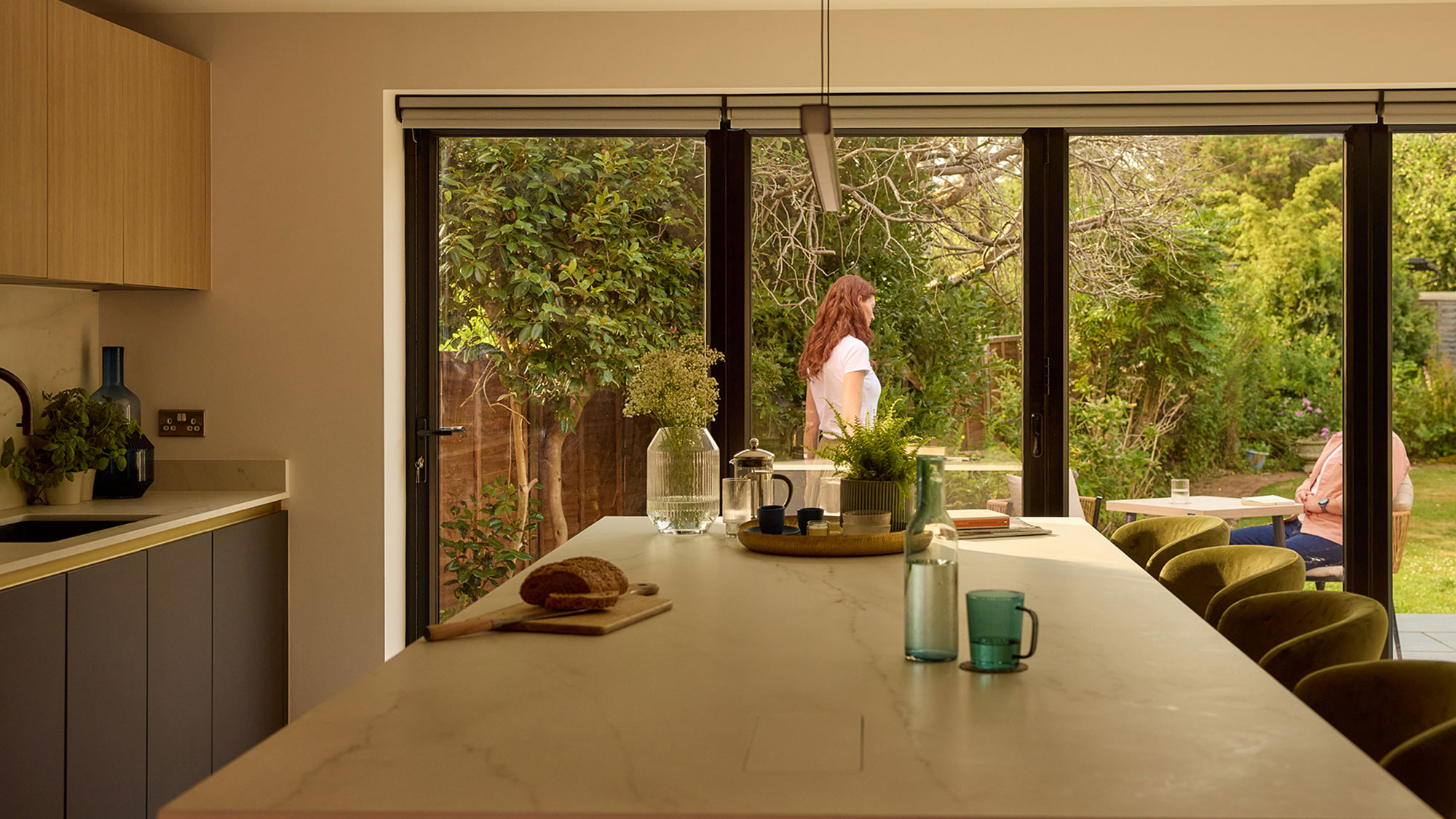 Modern kitchen with island unit and aluminium bifolding doors leading out to a patio and garden