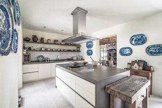 kitchen with butchers block and white cabinets and island with stainless steel worktop and blue plate collection on walls