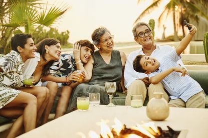 Grandson taking a group selfie of his family on vacation at luxury beach resort at sunset
