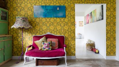 Vintage velvet sofa in front of wall with bold yellow floral wallpaper