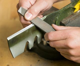 Sharpening a lawn mower blade by hand with a file