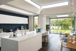 bright white open plan kitchen with glazing and a dark feature wall