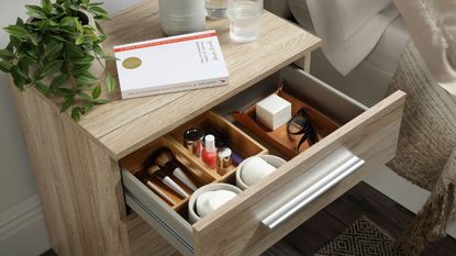 a bedaide table with a divider in it to seperate skincare products, a marie kondo book on top