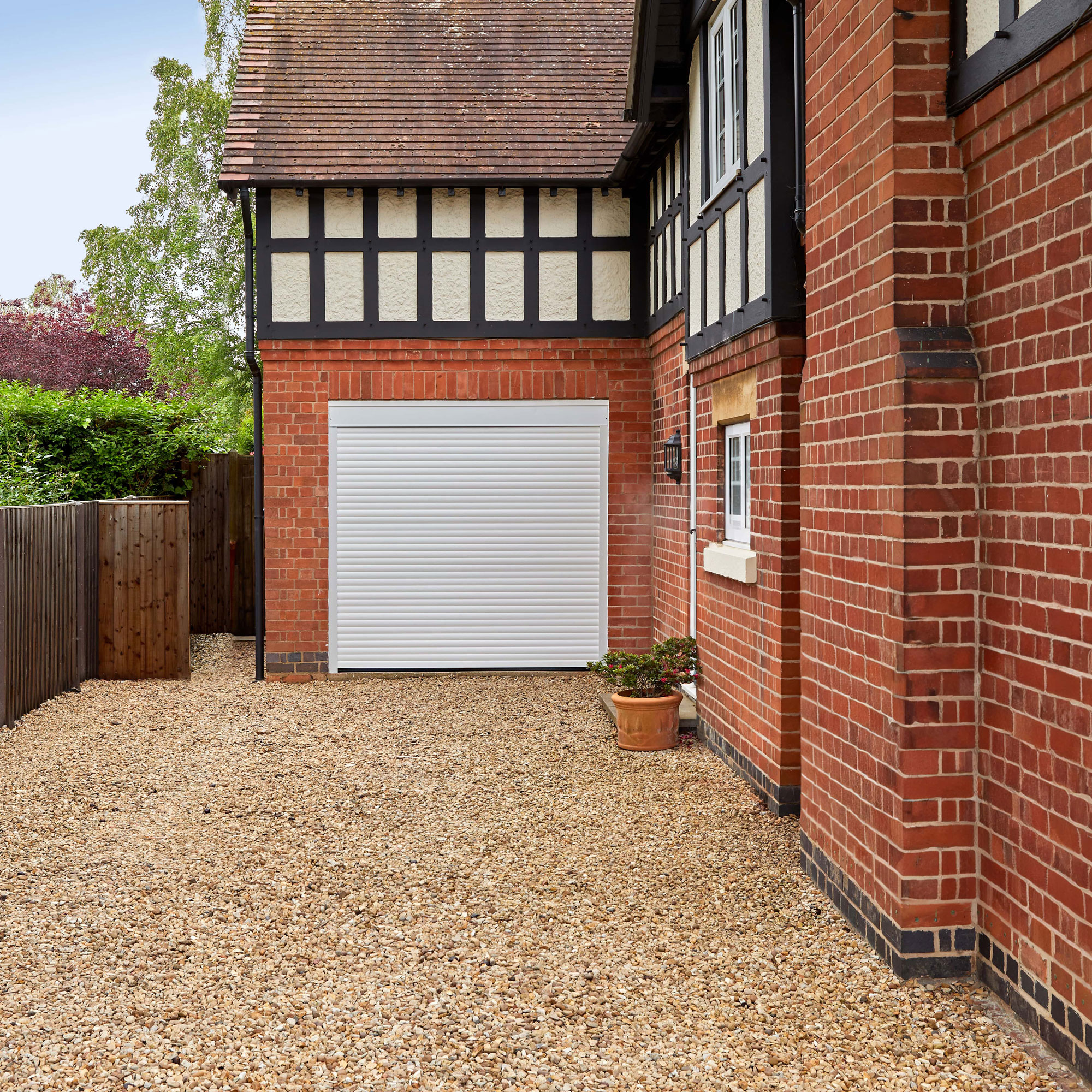 gravel driveway to brick house with up and over white garage door