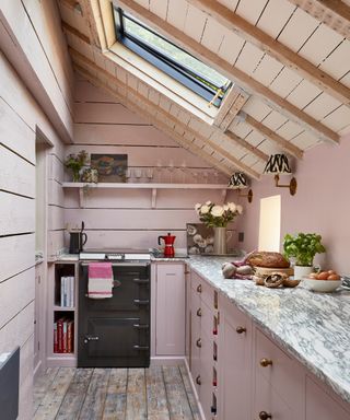 narrow pink cottage kitchen with vaulted ceiling, skylight , panelled walls and marble worktops