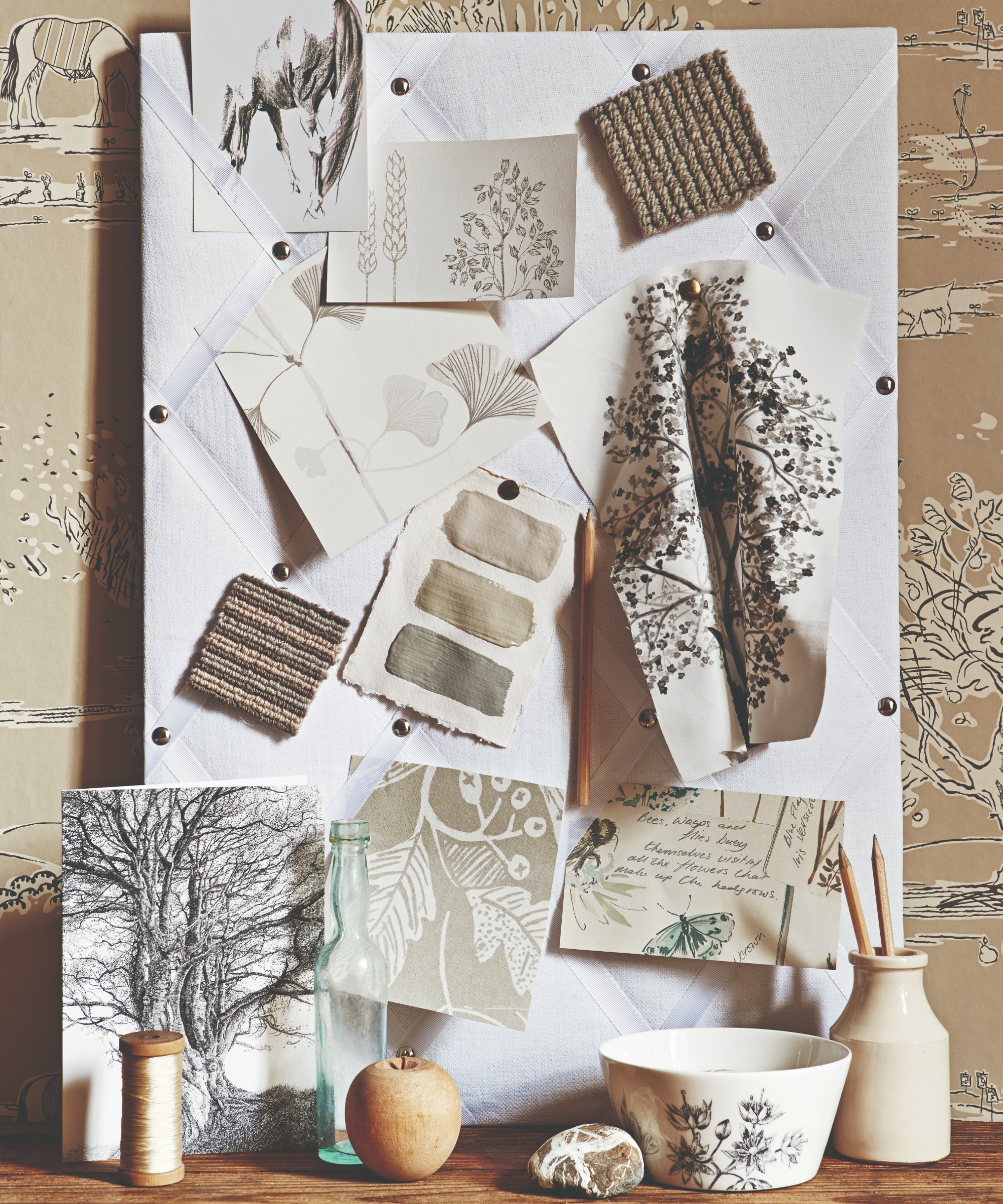 A mood board with paint, wallpaper and fabric samples set against a wallpapered wall