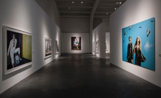 A gallery with large photos on white walls with black floors.