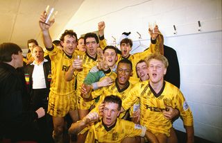 SUTTON, UNITED KINGDOM - JANUARY 07: Sutton United players including goalscorers Tony Rains (2nd left) and Matthew Hanlan (right, both hands raised) celebrate in the dressing room after the FA Cup 3rd Round match between Sutton United and Coventry City at Borough Sports Ground on January 7, 1989 in Sutton, England, Sutton produced one of the most famous 'giant-killings' in the competition's history, notable for being one of those rare occasions when a club from the highest tier of English football was defeated by a non-League side, Sutton won the match 2-1. (Photo by Simon Bruty/Allsport/Getty Images)