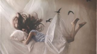 A dream-like image of a woman asleep in bed, with her hair and bedding flying about her as if she is floating in the air.