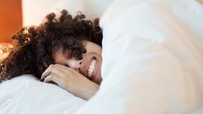 smiling woman in bed under the covers