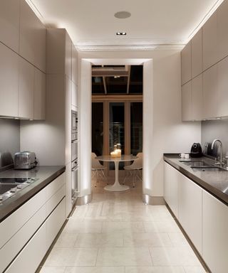 A modern galley style kitchen with recessed bright white LED lighting