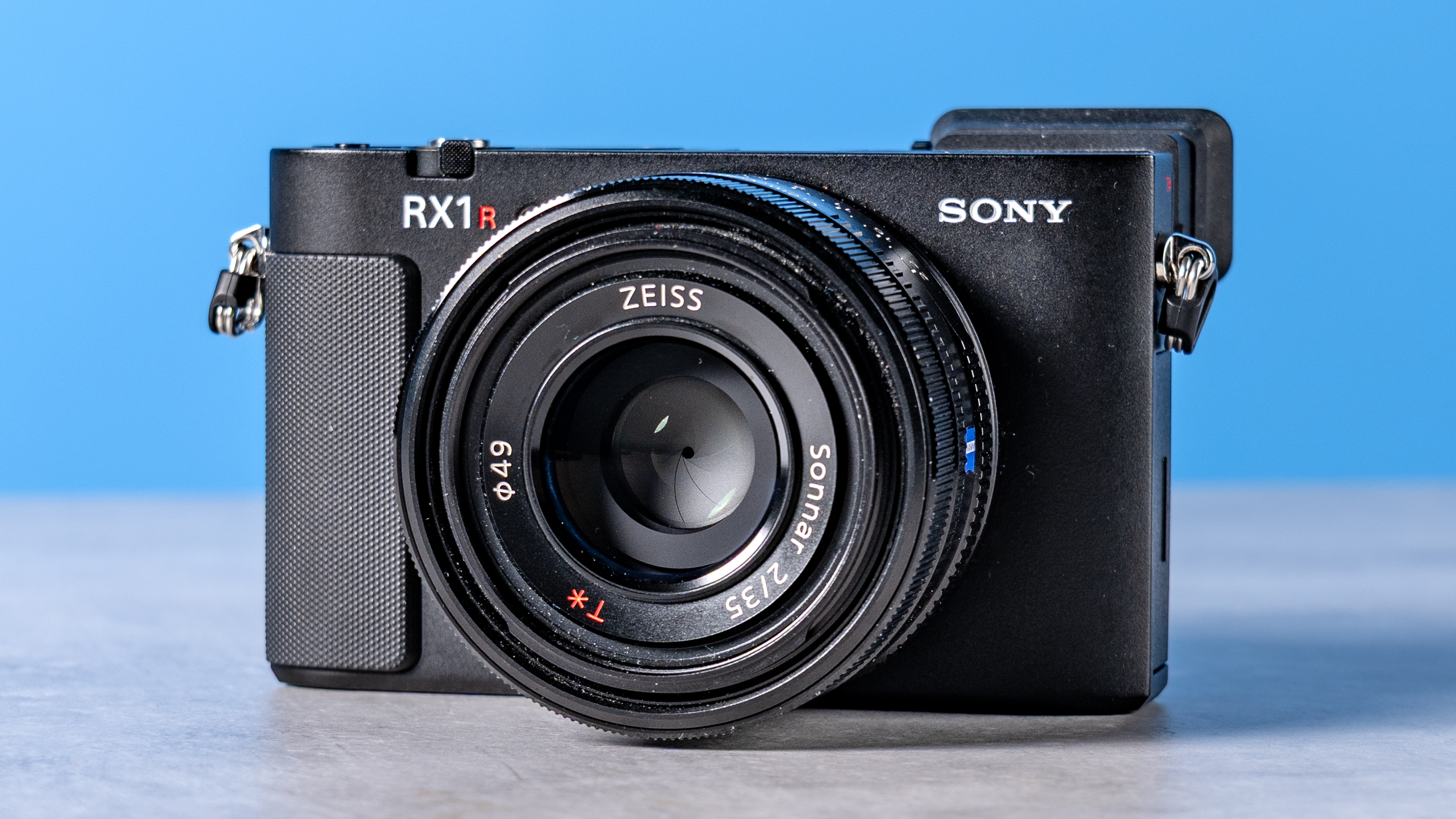 A photo of the Sony RX1R III on a stone surface with a blue background