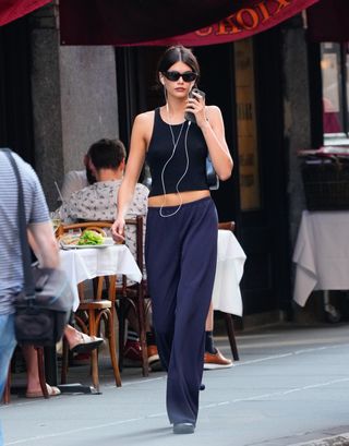 Kaia Gerber walks around New York City's soho neighborhood wearing a black tank top and navy pants