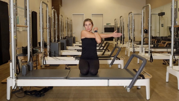 Woman on a Reformer Pilates machine demonstrating an exercise