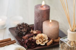 Cut out of aroma bottle diffuser with wooden sticks placed in front of lit brown candles