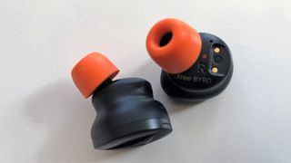 Beyerdynamic Free Byrd on a white background with orange eartips fitted