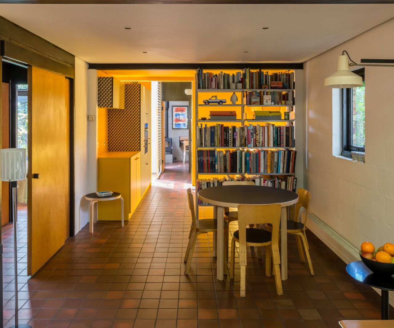 Before shots of 1 970s style single storey london house before a renovation and first floor extension. There is a lack of natural light but pops of bright yellow interiors a terracotta tiled floor and built in log burner
