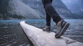 A hiker's feet as they cross a log over water
